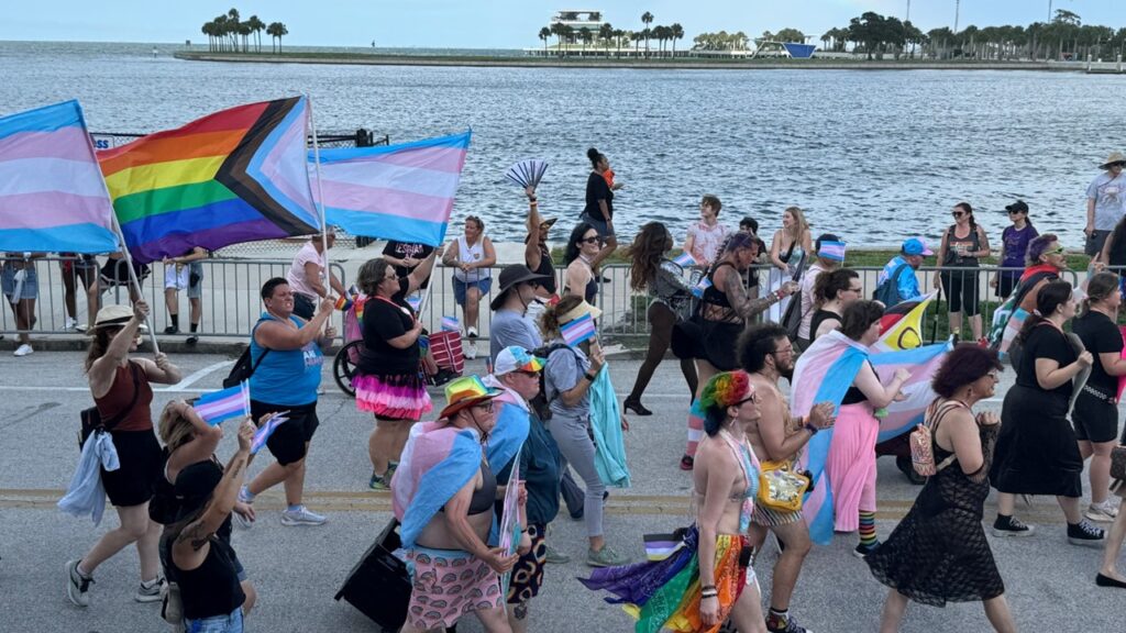 Community members marching with transgender and LGBTQIA+ flags at the 2024 St. Pete Pride Trans Pride March