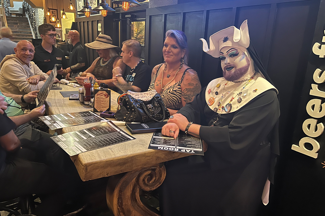 Sister Aura Babylon, a member of the Sisters of Perpetual Bliss, seated with attendees at The Hollander Hotel for a post-event dinner