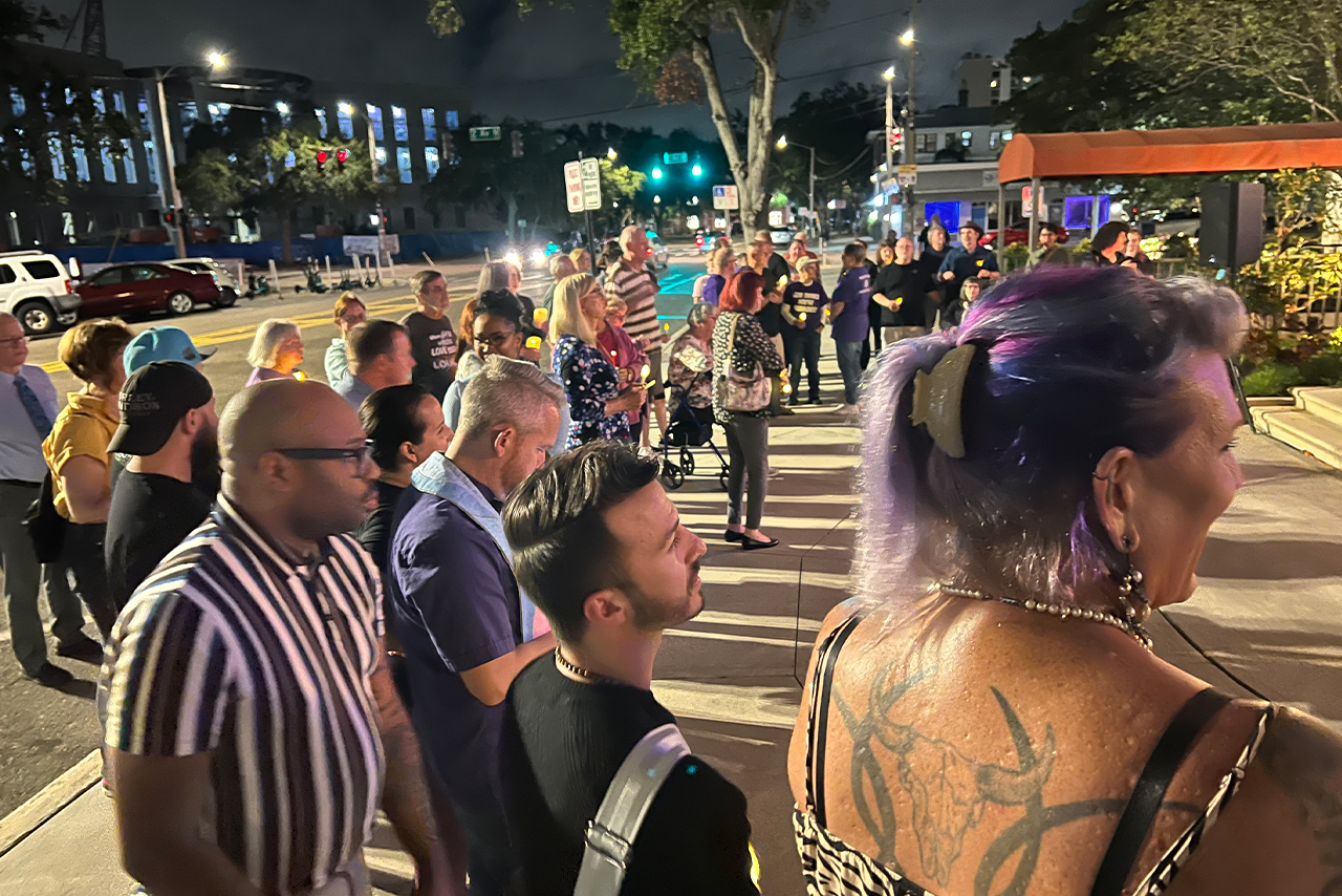 Eric Vaughn and other attendees standing outside St. Petersburg City Hall during the TDOR event, listening attentively to speakers.